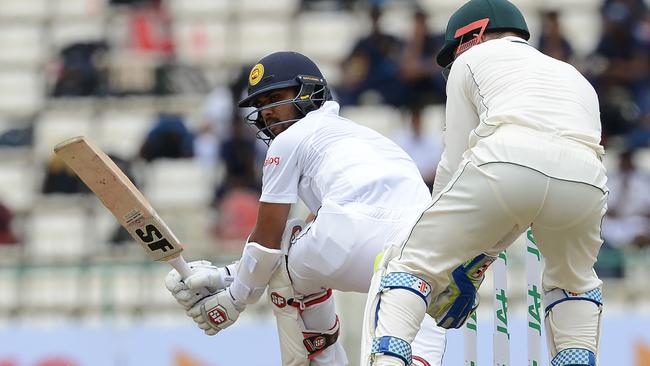 Sri Lanka's Dinesh Chandimal (L) plays a shot past Australia's wicketkeeper Peter Nevill.
