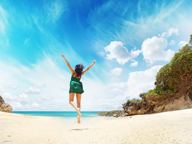 ESCAPE: Young cheerful woman in green dress jumping against cloudy sky, Geger Beach, Bali Picture: Istock