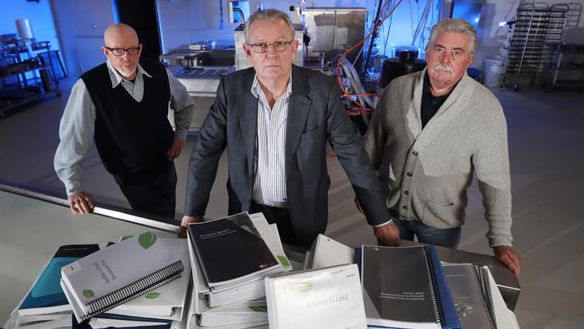 I Cook Foods principal Ian Cook (centre) in the preparation room at the business in Dandenong South. Retired Detective Sergeant Paul Brady (left) and retired Detective Inspector Rod Porter (right), with the mountain of evidence submitted to Victoria Police. Picture: Alex Coppel