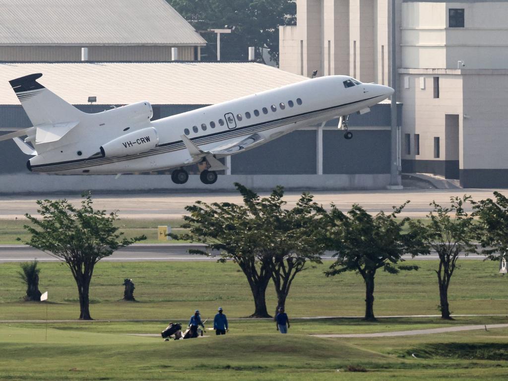 Golf players walk on a neighbouring golf course as a private jet, carrying the body of Shane Warne, departs from Don Mueang Airport in Bangkok. Picture: AFP