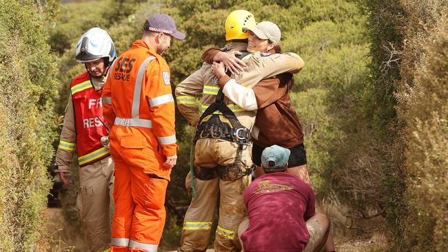 A dog owner hugs emergency service workers who rescued her golden retriever from a cliff near Bells Beach. Picture: Alison Wynd