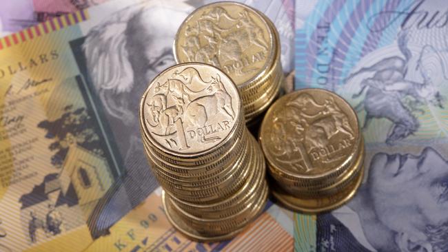 Three stacks of Australian one dollar coins on a background of bank notes. Shallow depth of field focus on tallest stack., cash money generic