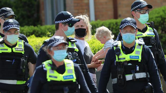 A woman and child look on as police swarmed the streets of Elwood on Saturday. Picture: Alex Coppel