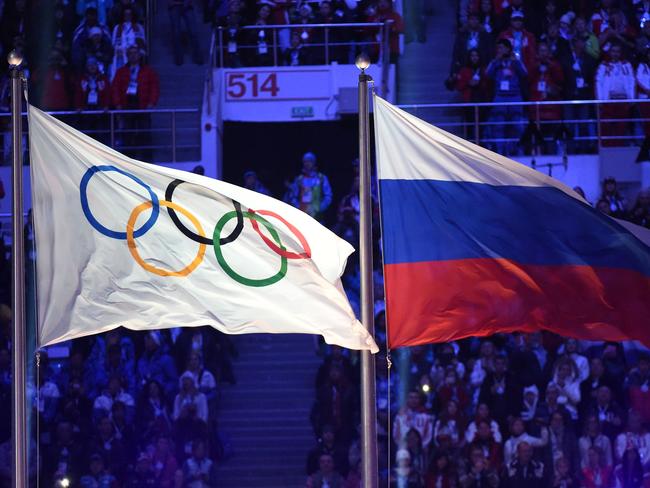 (FILES) In this file photo taken on February 23, 2014 The Olympic flag (L) and the Russian flag flutter during the Closing Ceremony of the Sochi Winter Olympics at the Fisht Olympic Stadium. - The World Anti-Doping Agency (WADA) decided on December 9, 2019, to exclude Russia from the Olympic Games for four years, including Tokyo-2020 and Beijing-2022, to sanction the falsification of test data submitted to the agency, a WADA spokesman said after the Executive Committee meeting in Lausanne. (Photo by Damien MEYER / AFP)