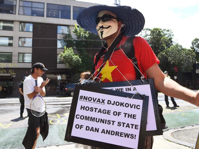 An anti-vax protester holds placards at a government detention centre where Serbia's tennis champion Novak Djokovic is reported to be staying in Melbourne. Picture: AFP)