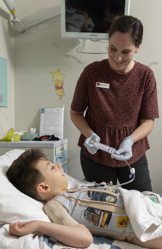 Nurse Grace Fitzgerald administers medicine to Oscar. A gastrostomy button connects the outside to inside of stomach. Picture: Monique Harmer