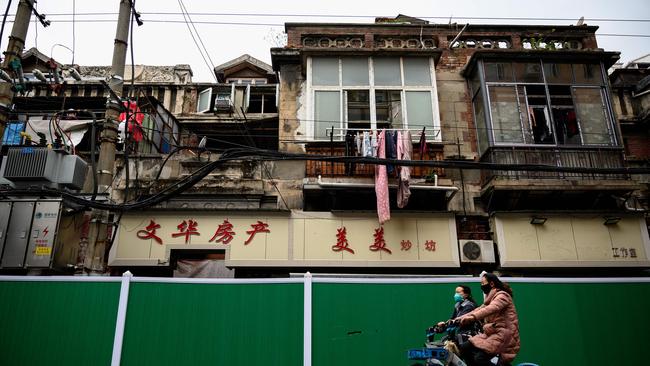 Women cycle alongside a shuttered street in Wuhan. Picture: AFP.