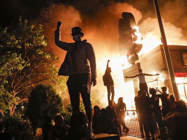 Protesters demonstrate outside of a burning fast food restaurant, early Friday, May 29, 2020, in Minneapolis. Picture: John Minchillo