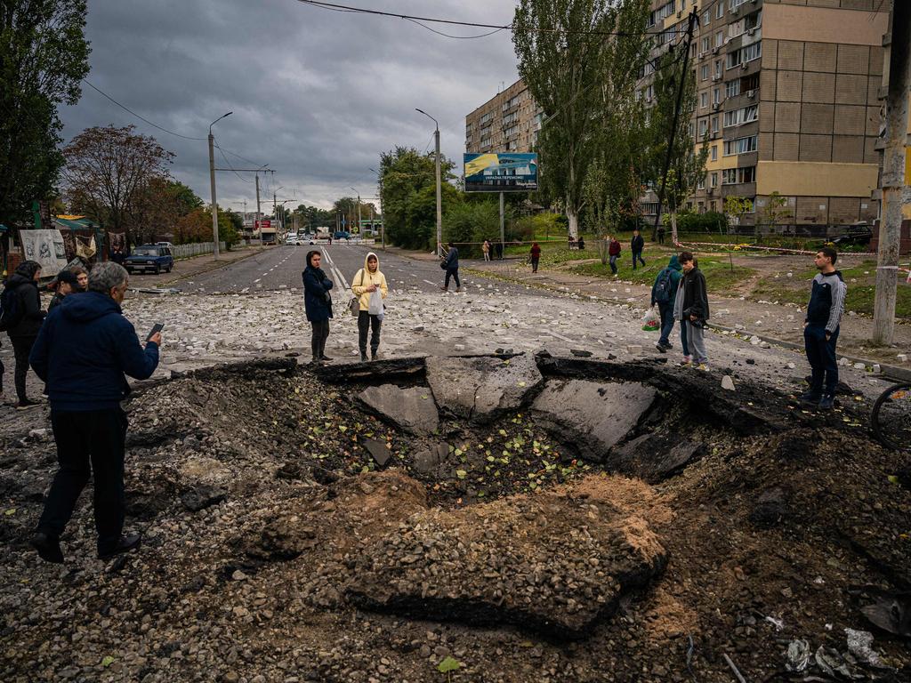 Local residents examine a crater following a missile strike in Dnipro. The head of the Ukrainian military said that Russian forces launched at least 75 missiles at Ukraine on Monday morning. Picture: AFP