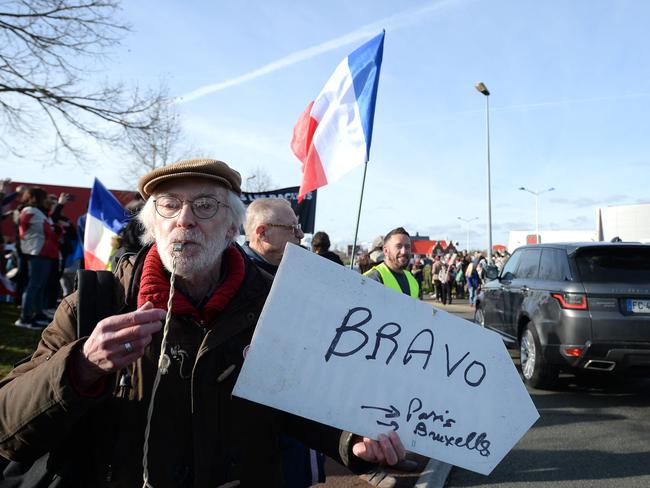 A protester holds a placard reading "Congratulations, Paris, Brussels" as a Freedom Convoy (Convoi de la Liberte) passes through Le Mans, western France. Picture: AFP