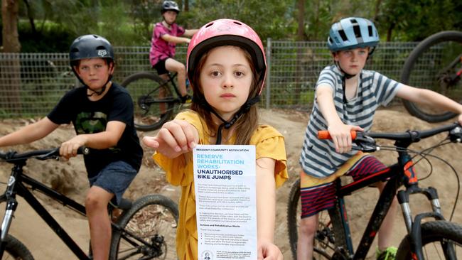 Gabe Kenna (left), Ryan Hawkins (back), Lilou Robbins (centre) and Riley Kenna (right) at their local BMX track they built in Caringbah. Lilou holds a pamphlet that was letter box dropped in the local area from council. Picture: Toby Zerna