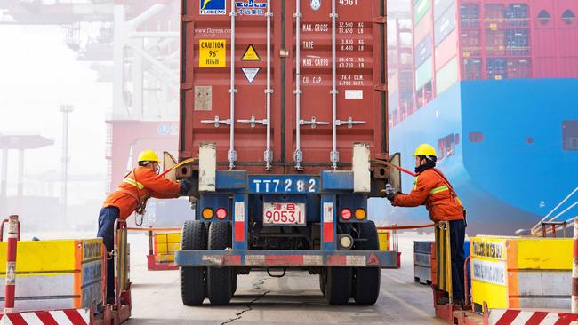 Workers prepare a container at the port in Qingdao, China's eastern Shandong province, on January 14, 2019. - China's global trade volume rose last year but its surplus fell again as its imports outpaced its exports, official data released on January 14 showed amid a bruising trade war with the United States. (Photo by STR / AFP) / China OUT