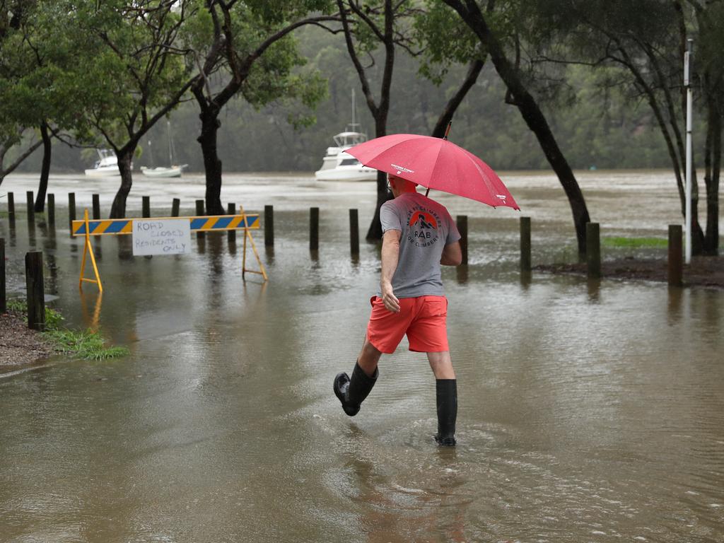 Neil Muckle walks through the rising water at Picnic Point. Picture: John Grainger