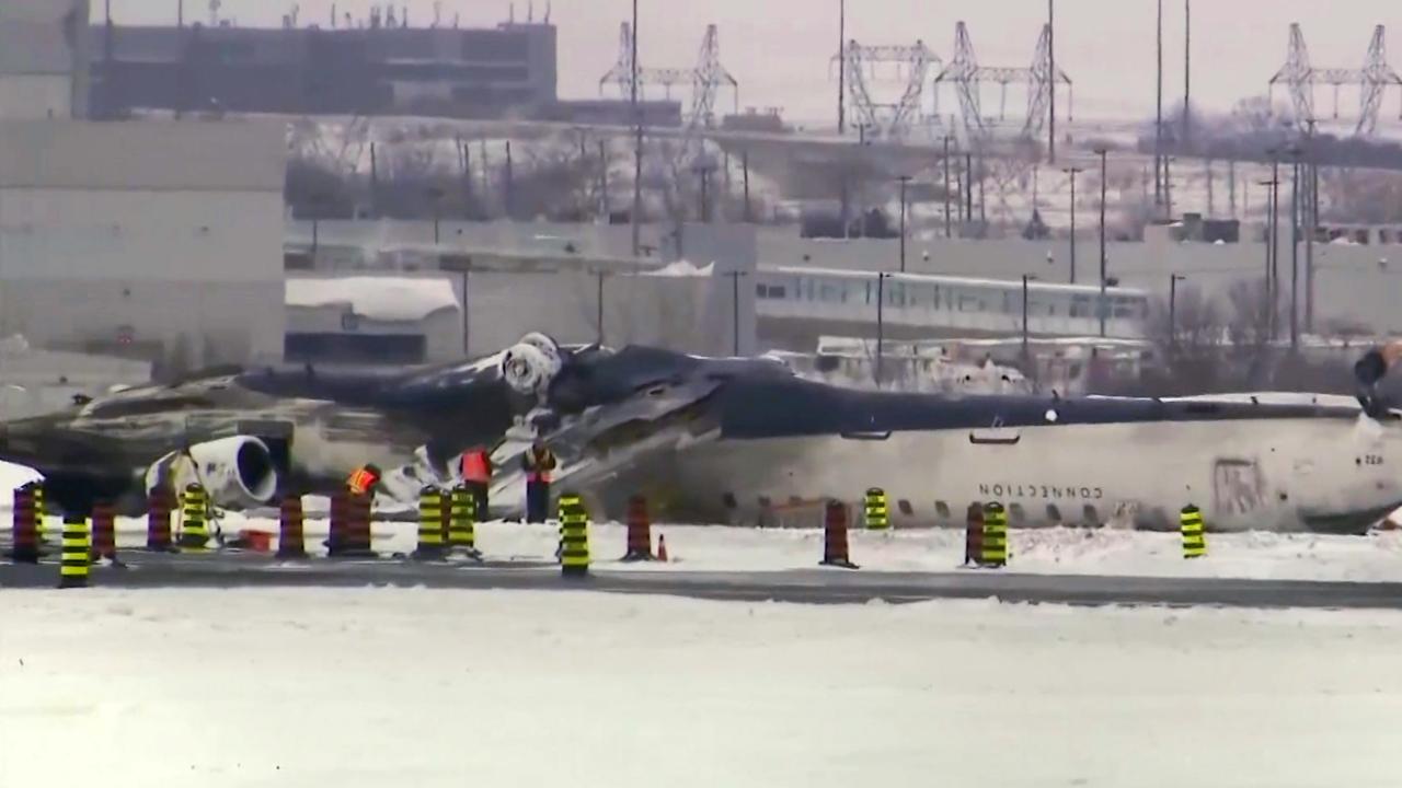 This image taken from video provided by CTV shows workers near the crashed Delta passenger jet on a tarmac of the Toronto Pearson Airport in February. Picture: CTV via AP.