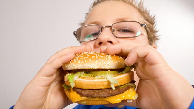 Young fat school boy eating hamburger