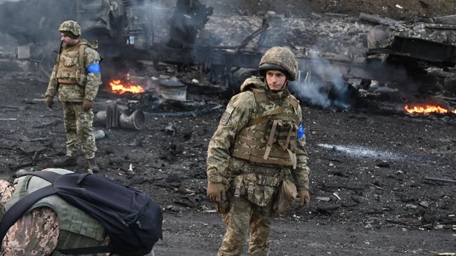 Ukrainian service members look for and collect unexploded shells after fighting with Russian forces. Picture: AFP