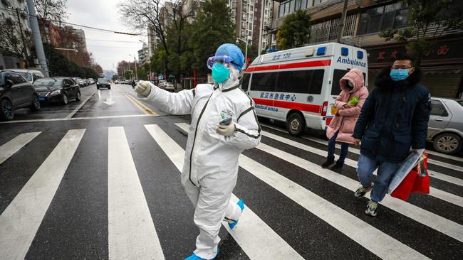 A fully protected nurse walks a patient off the ambulance in Wuhan, where the Chinese national women’s soccer team visited a week ago. Picture: Getty