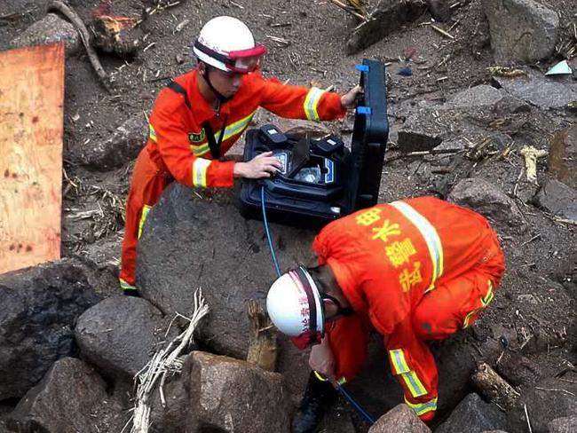 Rescuers use detectors to scan for potential survivors at the site following a landslide in Taining county in southeast China's Fujian province, Sunday, May 8, 2016. Rescuers on Sunday searched for 34 construction workers missing in a landslide at the site of a hydropower project following days of heavy rain in southern China. Seven other workers were pulled out alive, officials and state-run media reported. (Chinatopix via AP) CHINA OUT