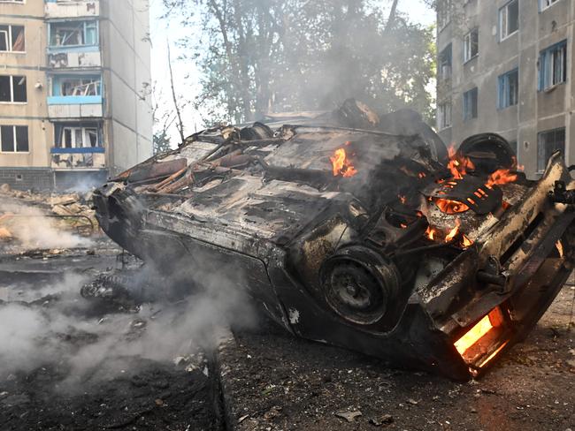 A burnt-out car is seen in the courtyard of a damaged residential building following a missile attack in Kharkiv on August 30, 2024. Russian strikes killed at least six people in the eastern Ukrainian city of Kharkiv, including a 14-year-old girl at a playground, and wounded dozens more, officials said on August 30, 2024. (Photo by SERGEY BOBOK / AFP)