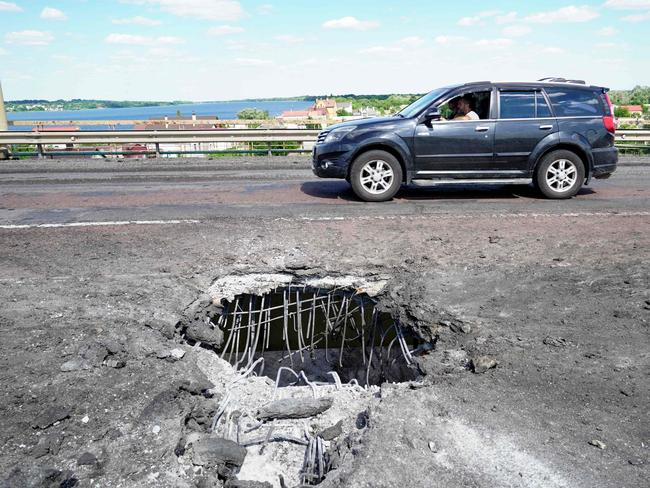 A car moving past a crater on Kherson's Antonovsky bridge across the Dnipro river caused by a Ukrainian rocket strike. Picture: AFP