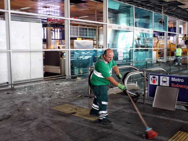 Workers clean the debris from yesterday's blasts as they take a break at Turkey's largest airport, Istanbul Ataturk. Picture: Getty