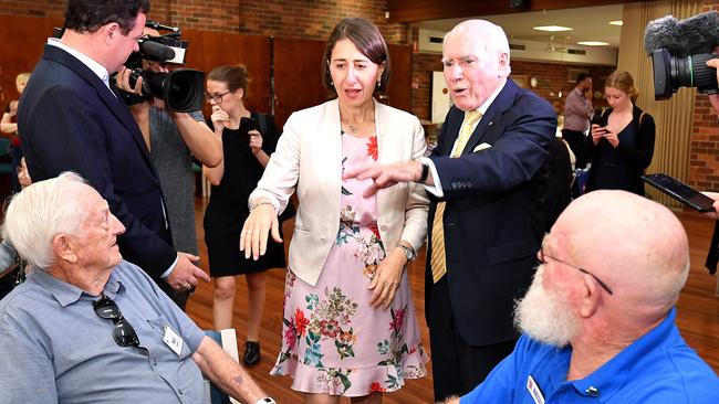 Premier Gladys Berejiklian (centre) reacts alongside former Prime Minister John Howard 