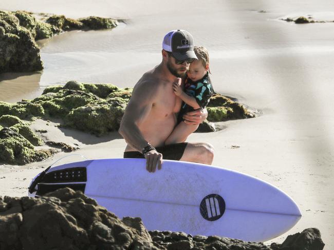 Hemsworth juggled son Tristan in one hand as he prepared his board for a surf. Picture: Media Mode