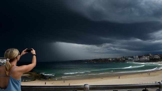 A woman is seen taking a photograph as storm clouds build over Bondi beach, in Sydney, Friday, Nov. 13, 2015. The Bureau of Meteorology has issued a severe storm warning for thunderstorms and heavy rain for the Sydney metropolitan area as well as the Hunter, Illawarra and mid-north coast regions. (AAP Image/Dan Himbrechts) NO ARCHIVING