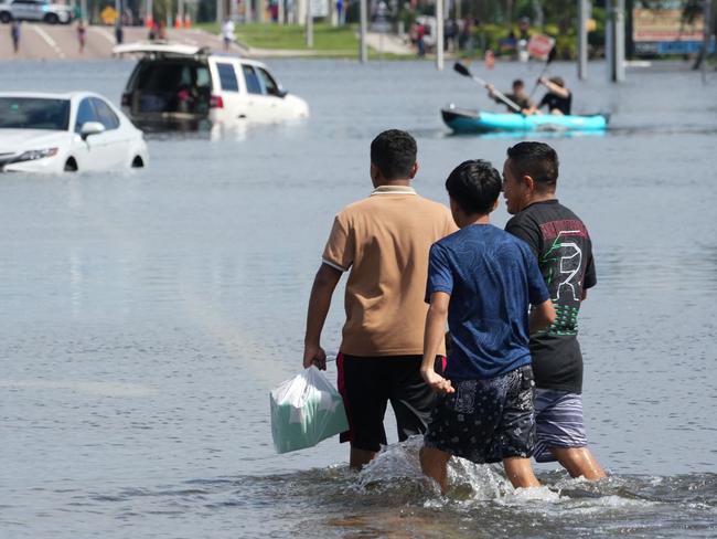 Kids walk past vehicles flooded in the water as the streets of the Southeast Seminole Heights section of Tampa due to Hurricane Milton on October 10, 2024 in Florida. Hurricane Milton tore a coast-to-coast path of destruction across the US state of Florida, whipping up a spate of deadly tornadoes that left at least four people dead, but avoiding the catastrophic devastation officials had feared. (Photo by Bryan R. SMITH / AFP)