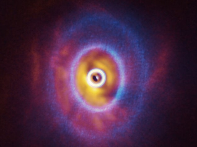 ALMA, in which ESO is a partner, and the SPHERE instrument on ESO’s Very Large Telescope have imaged GW Orionis, a triple star system with a peculiar inner region. Unlike the flat planet-forming discs we see around many stars, GW Orionis features a warped disc, deformed by the movements of the three stars at its centre. This composite image shows both the ALMA and SPHERE observations of the disc.  The ALMA image shows the disc’s ringed structure, with the innermost ring (part of which is visible as an oblong dot at the very centre of the image) separated from the rest of the disc. The SPHERE observations allowed astronomers to see for the first time the shadow of this innermost ring on the rest of the disc, which made it possible for them to reconstruct its warped shape.