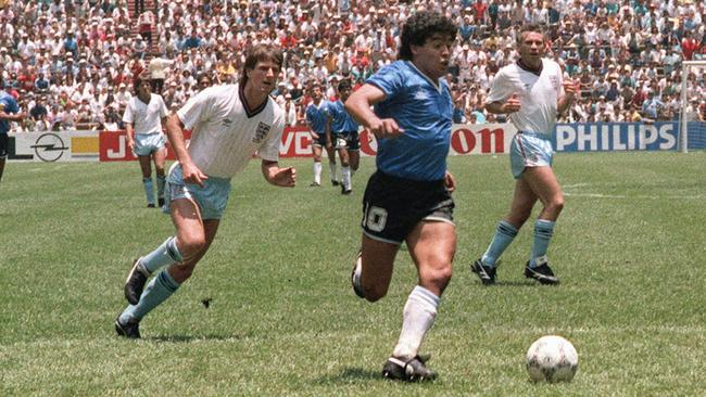 (FILES) In this file photo taken on June 22, 1986 Argentinian forward Diego Armando Maradona runs past English defenders Terry Butcher (L) and Terry Fenwick (2nd L) on his way to scoring his second goal during the World Cup quarterfinal soccer match between Argentina and England.Argentina advanced to the semifinals with a 2-1 victory.  AFP PHOTO - Argentinian football legend Diego Maradona passed away on November 25, 2020 (Photo by STAFF / AFP)