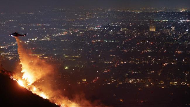 A firefighting helicopter drops water as the Sunset Fire burns in the Hollywood Hills with evacuations ordered. Picture: AFP