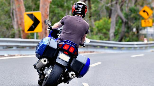 A rider passes the scene where a motorcyclist was killed in January after coming off his bike on the Old Pacific Highway at Cowan, Sydney, Tuesday, Jan. 23, 2018. (AAP Image/Joel Carrett)