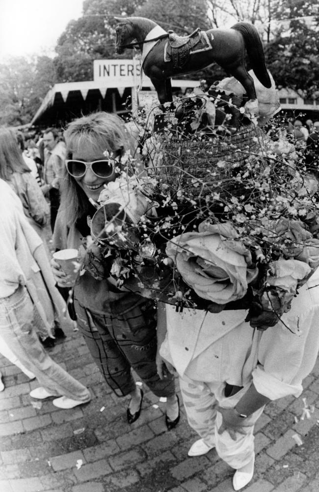 A woman wears a large hat adorned with a horse in 1986.