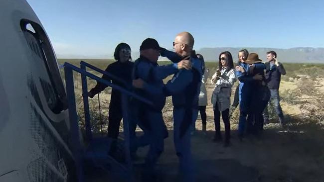 William Shatner (CL) gets a hug from Blue Origin founder Jeff Bezos after landing in the West Texas region.