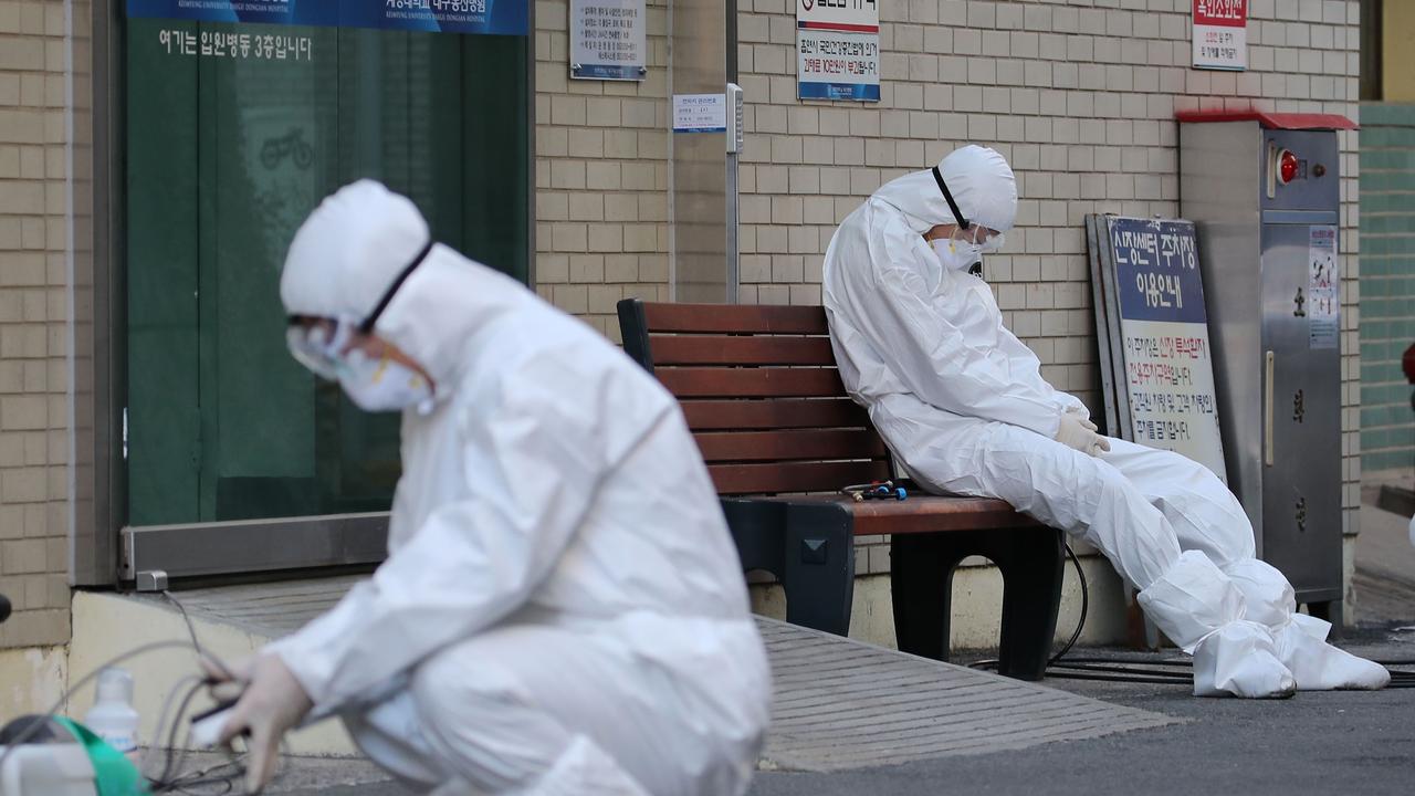 A medical worker wearing protective gear takes a rest as he waits for ambulances carrying patients infected with the COVID-19. (Photo by – / YONHAP / AFP)