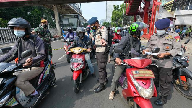 Police and military officers check motorcyclists heading into Jakarta’s CBD on Thursday. Picture: AFP