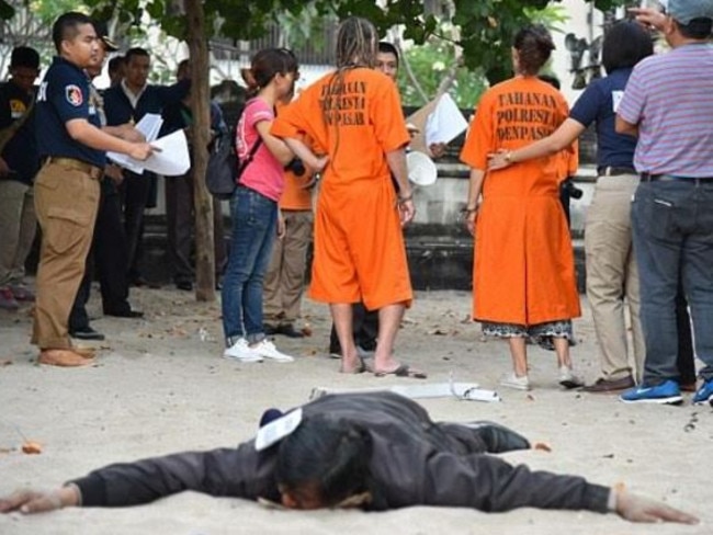 David Taylor and Sara Connor and an officer in the foreground who appears to be playing that he is unconscious during the re-enactment at Kuta Beach.