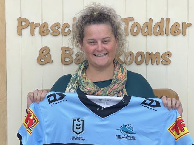 Stevie King of 3 Bears Cottage Early Education Service with a signed Cronulla Sharks jersey. They are raffling off the jersey to raise money for the Orara Valley Dingoes Football Club.