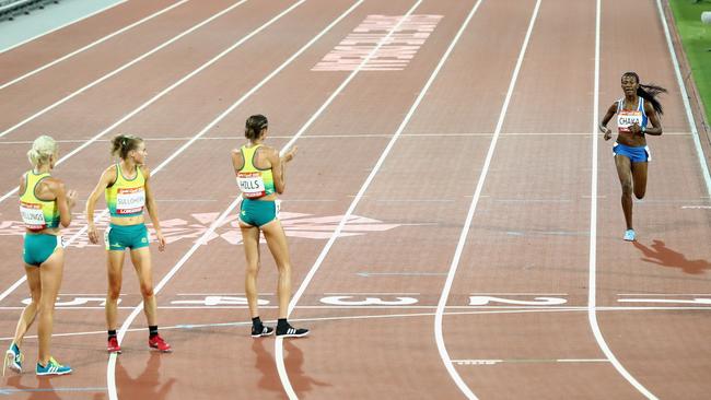 Lineo Chaka of Lesotho is applauded by Australian competitors Eloise Wellings, Celia Sullohern and Madeline Hills at the finish of the women’s 10,000m last night. Photo: Getty Images