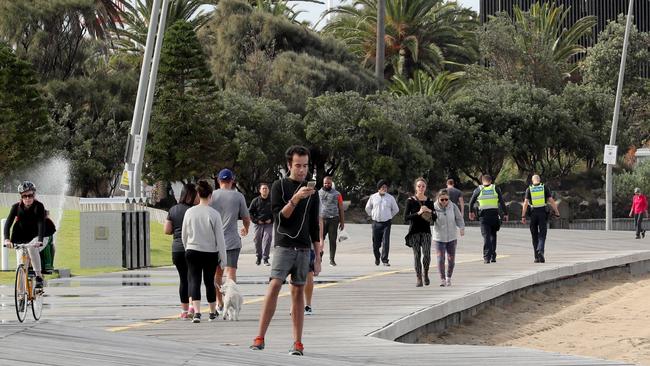 Police patrol the St Kilda beach foreshore after the beach was closed on Friday. Picture: David Geraghty.