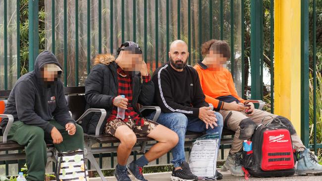 Sam Haddad (centre, black jumper with white stripe) waits for a train at Emu Plains after being released on bail from Amber Laurel Correctional Centre. Picture by Max Mason-Hubers