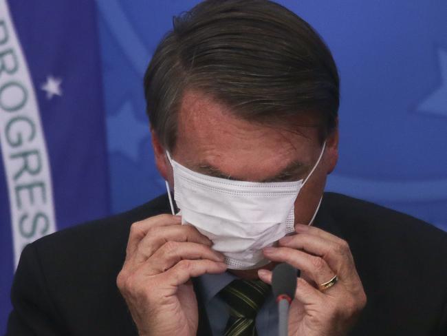 BRASILIA, BRAZIL - MARCH 18:  President of Brazil Jair Bolsonaro adjusts his protective mask during a press conference regarding government plans and measures about the Coronavirus (COVID-19) Outbreak in Brazil, at the Planalto Palace on March 18, 2020 in Brasilia, Brazil. (Photo by Andre Coelho/Getty Images)