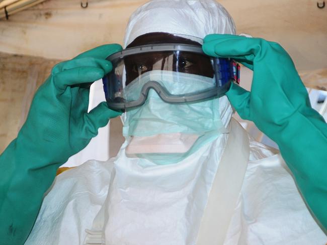 (FILES) -- A file photo taken on June 28, 2014 shows a member of Doctors Without Borders (MSF) putting on protective gear at the isolation ward of the Donka Hospital in Conakry, where people infected with the Ebola virus are being treated. Guinea announced on August 9, 2014 it was closing its land borders with Liberia, Sierra Leone over Ebola fears. AFP PHOTO / CELLOU BINANI