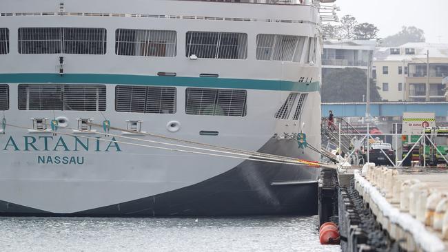 A passenger walks from the MV Artania to be attended to by waiting paramedics on the wharf at the Fremantle Passenger Terminal today. Picture: Getty Images