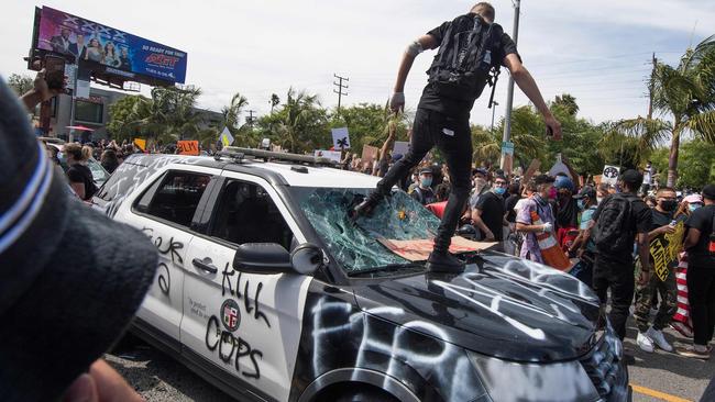 Demonstrators smash a police car in Los Angeles, California. Picture: AFP