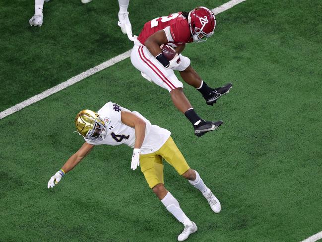 ARLINGTON, TEXAS - JANUARY 01: Running back Najee Harris #22 of the Alabama Crimson Tide leaps cornerback Nick McCloud #4 of the Notre Dame Fighting Irish during the first quarter of the 2021 College Football Playoff Semifinal Game at the Rose Bowl Game presented by Capital One at AT&T Stadium on January 01, 2021 in Arlington, Texas. (Photo by Carmen Mandato/Getty Images)