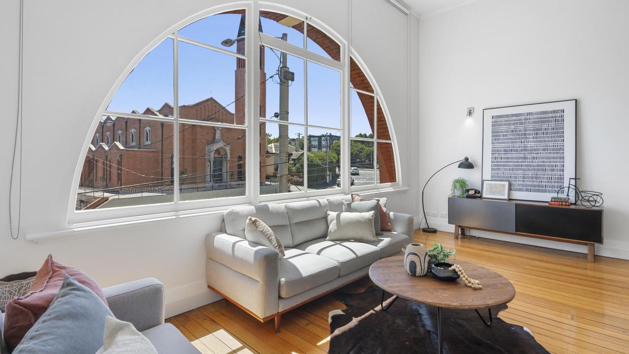 Semicircular windows flood the tram depot home with light.