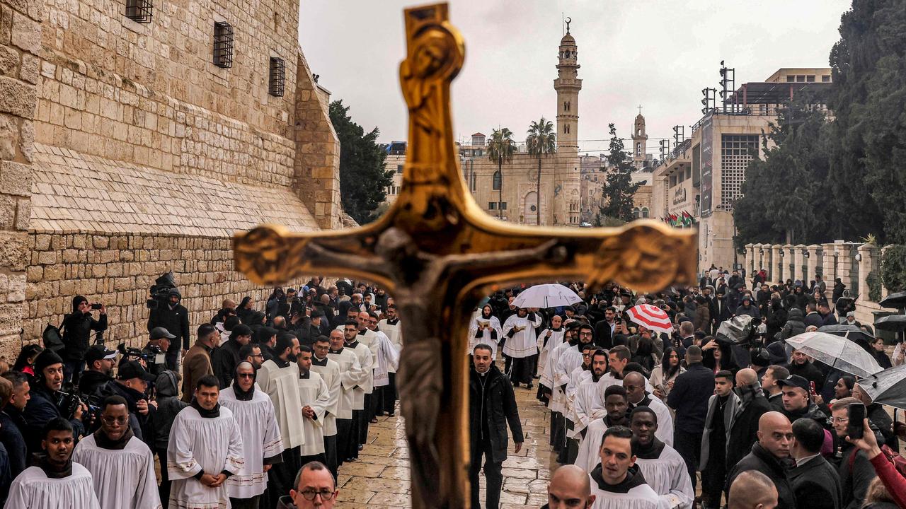 A crucifix is raised as deacons and other Catholic worshippers congregate for Christmas Eve outside the Church of the Nativity in Bethlehem. Picture: Hazem Bader/AFP