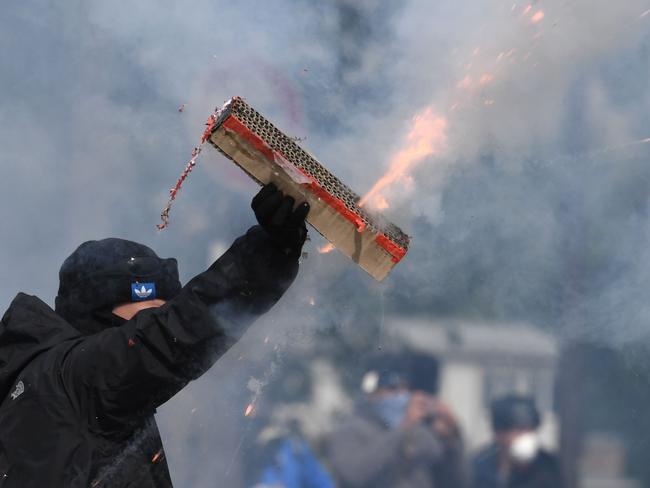 A protester holds a strip of fireworks as they explode for the annual May Day workers' rally in Paris. Picture: AFP/Alain Jocard